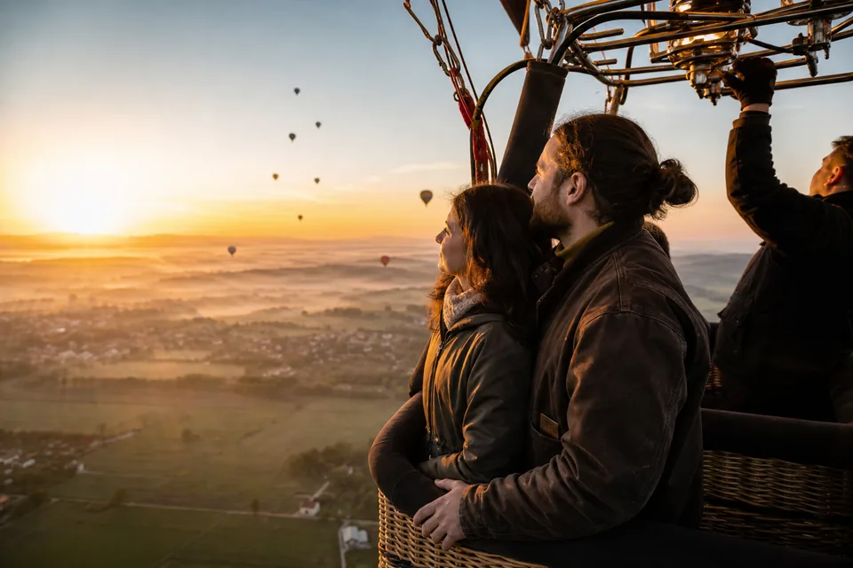 Para dorosłych w koszu balonu podziwia wschód słońca nad polami pod Krakowem
